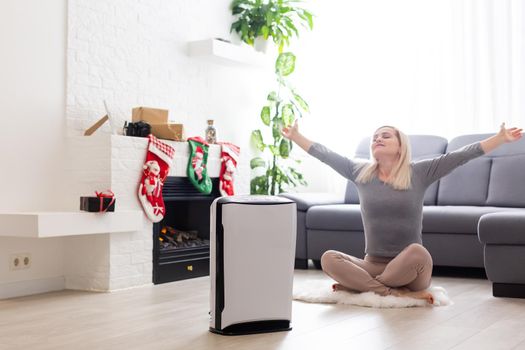 Air purifier in a living room, woman working with laptop with filter for clean room