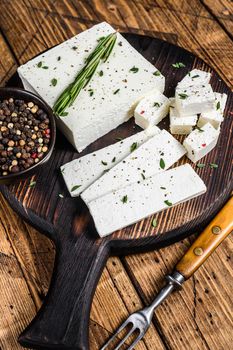 Cut cheese feta with rosemary on a wooden cutting board. wooden background. Top view.