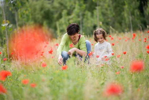 Happy mother with her little daughter in poppy field