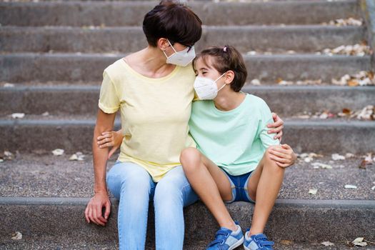 Middle-aged mother and daughter sit on the street wearing masks because of the Covid-19 pandemic