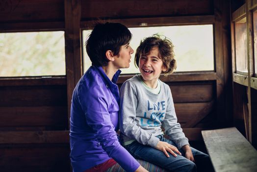 Mother with her seven year old daughter laughing in a cabin in the countryside. Lifestyle concept.
