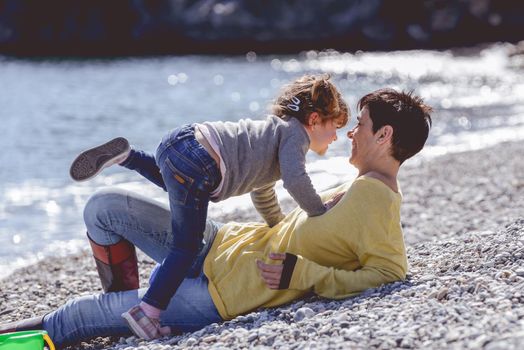 Portrait of mother and her little daughter having fun on the beach