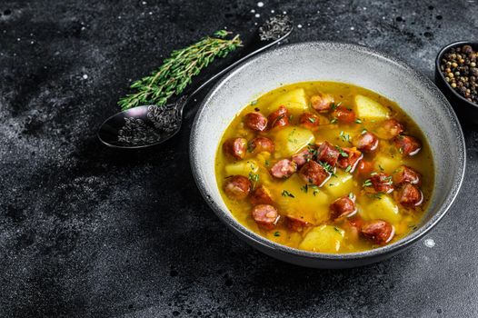 German Split pea soup with smoked sausages and meat. Black background. Top view. Copy space.