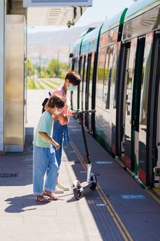 Mother and daughter riding on a train with an electronic scooter Concept of ecomobility.