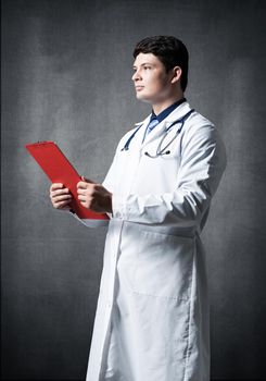 Doctor with tablet for documents, scans documents against the background of the wall