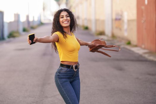 Happy Arab woman wearing casual clothes with open arms in the street.