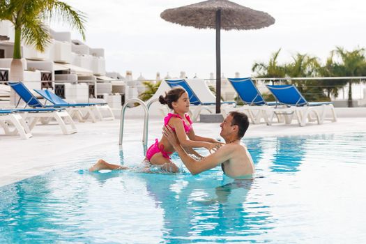 Father playing with his daughter in swimming pool.