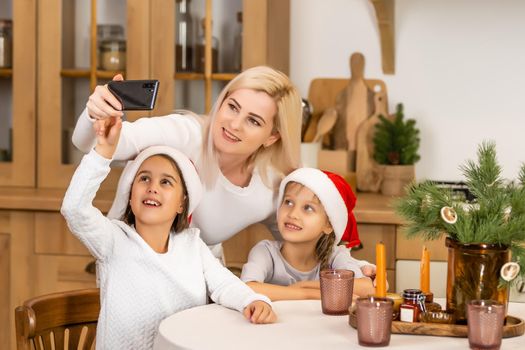 Christmas online family congratulations. Smiling european blonde mother and daughter using mobile tablet for video call friends and parents.