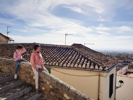 Mother and daughter sitting on a balcony enjoying the views of Granada from the Realejo neighborhood.