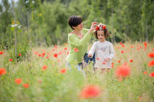 Happy mother with her little daughter in poppy field