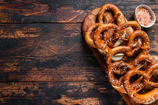 Homemade Soft Pretzels with Salt on a wooden board. Dark wooden background. Top view. Copy space.