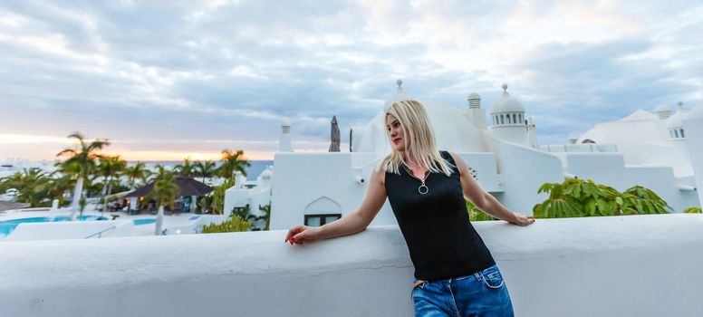 Young girl standing on the balcony overlooking the sea.