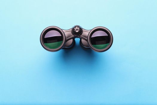 Top view of binoculars equipment placed on blue background with shadow. Necessary tool for explorers and travelers. Search and find, traveling concept