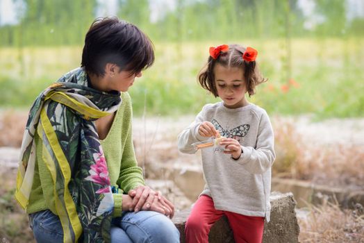 Happy mother with her little daughter picnicking