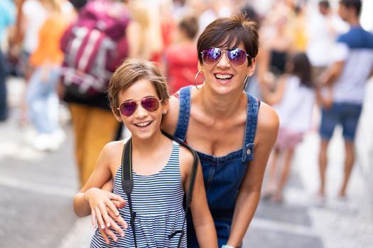 Mother and her little daughter traveling together in urban background. Women wearing sunglasses.
