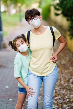Middle-aged mother and daughter standing on the street wearing masks because of the Covid-19 pandemic