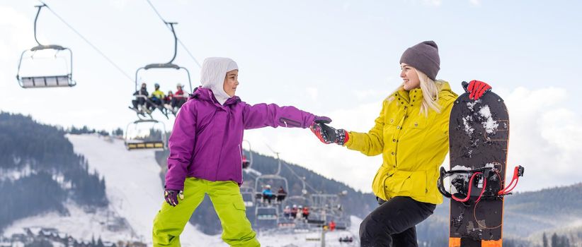 mother and daughter with snowboards at winter resort