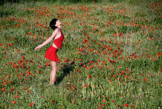 A girl dressed in red in a field of poppies