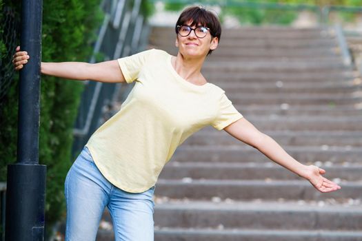 Funny happy middle-aged woman wearing eyeglasses in an urban park.