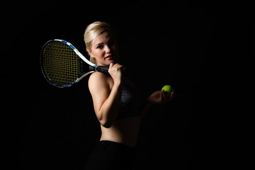 Female tennis player with racket and ball on black background