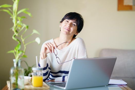 Smiling woman teleworking from home with her laptop. Female in her 50s