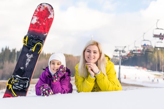 mother and daughter with snowboards in a mountain resort