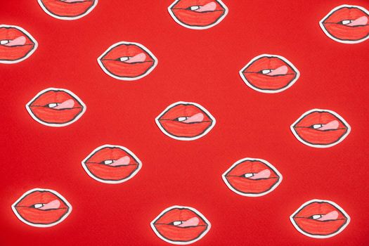 Female mouth shaped painted stickers placed on red surface as abstract background