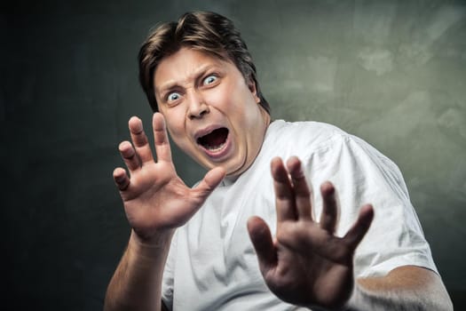 handsome man scared over dark grey background