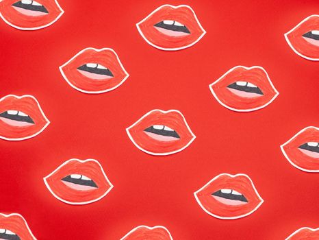 Female mouth shaped painted stickers placed on red surface as abstract background