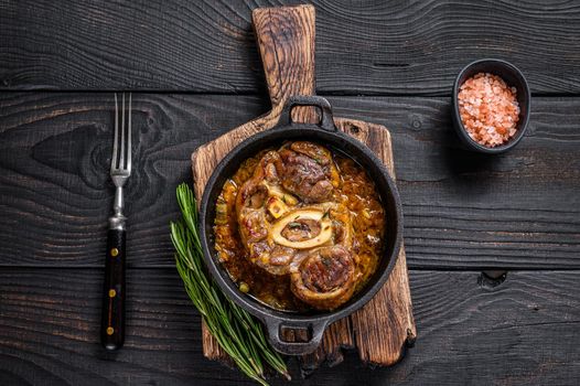 Stew veal shank meat OssoBuco, italian osso buco steak. Black wooden background. Top view.