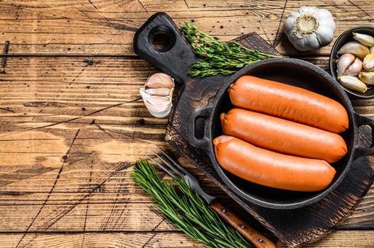 Sausages bratwurst from pork meat in a pan. wooden background. top view. Copy space.