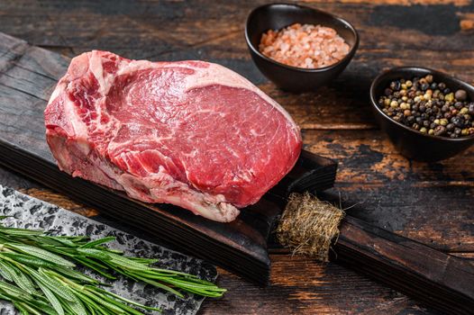 Raw beef meat Club or striploin on the bone steak. Dark wooden background. Top view.