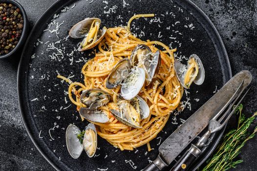 Seafood Spaghetti pasta with Clams vongole in a plate. Black background. Top view.