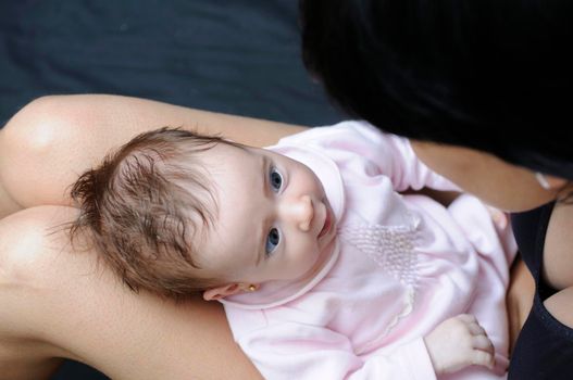 Baby girl two months old looking at her mother on her legs.