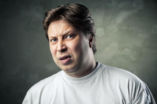 Man with disgusted expression over dark grey background