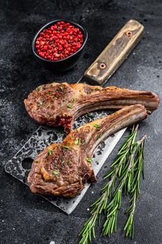 Barbecue grilled lamb chops on a butcher meat cleaver. Black background. Top view.