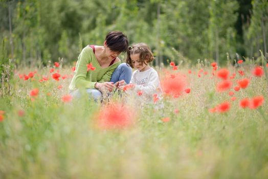 Happy mother with her little daughter in poppy field