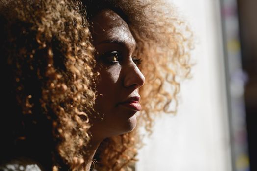 Close-up portrait ofl young African American woman with afro hairstyle and green eyes