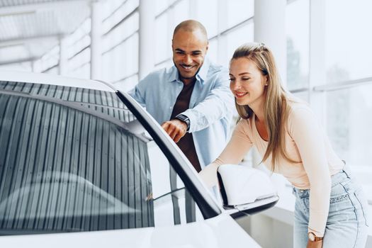 Young happy couple choosing a new car in car dealership