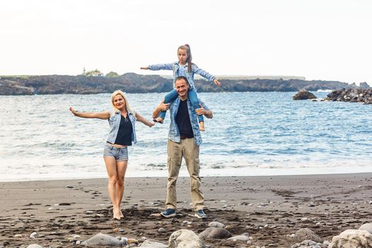 Happy family standing on the beach on the dawn time