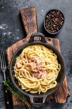Pasta Carbonara with bacon and parmesan in a pan. Black background. top view.