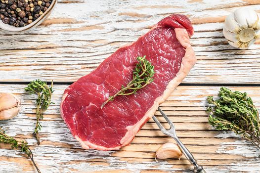 New York steak or striploin with herbs, raw beef. White wooden background. Top view.