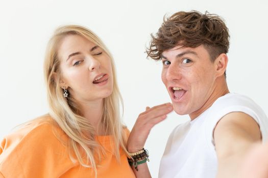 Portrait of a cute positive cheerful young couple of students taking selfie on a smartphone or camera. The concept of a passionate young couple in love with students