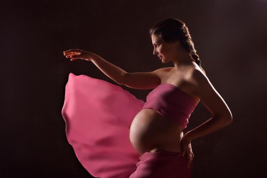 Portrait of beautiful pregnant woman in pink chiffon shawl