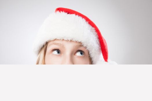 Beautiful christmas woman in santa hat holding empty board and looking to the right isolated on white background