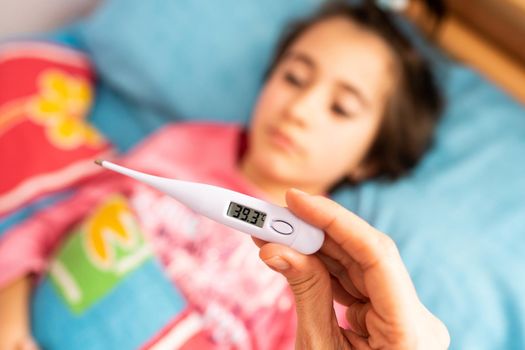 Mother measuring her toddler's temperature with a digital thermometer to check for fever