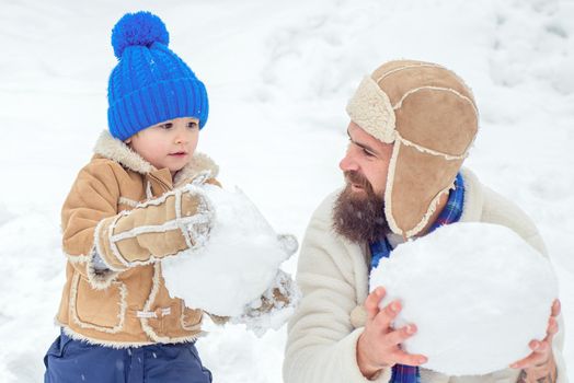 Winter, father and son play outdoor. Happy family plaing with a snow on a snowy winter walk. Father and son making snowball on winter background