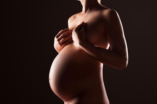 Pregnant woman silhouette over black background. Side view