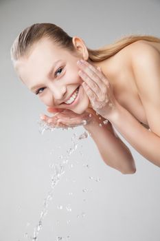 Closeup portrait of a beautiful woman washing her clean face with water