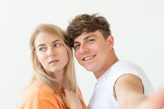 Portrait of a cute positive cheerful young couple of students taking selfie on a smartphone or camera. The concept of a passionate young couple in love with students